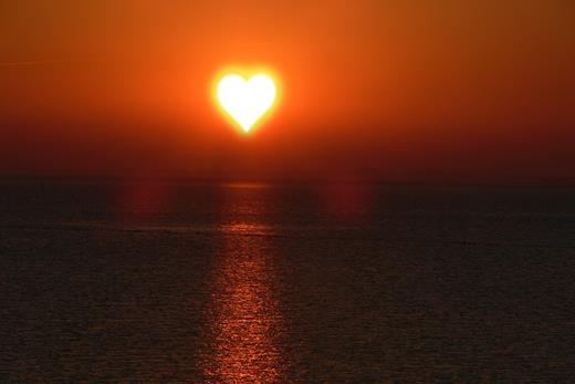 Zachód Słońca w kształcie serca nad morzem